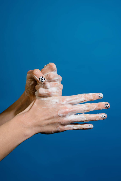 Close-up foto van handen met zeep geïsoleerd over blauwe muur - Foto, afbeelding