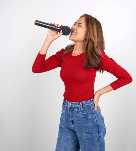 Joven asiática mujer en rojo manga larga camiseta cantando con micrófono. - Foto, Imagen