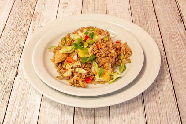 Square white plate of Latin American chaufa rice with vegetables, scrambled eggs, and fried chicken - Foto, afbeelding