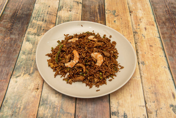 Receta de arroz chaulafán ecuatoriano con gambas, pollo frito y verduras sobre mesa de madera - Foto, imagen