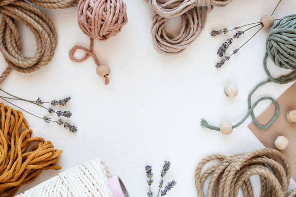 Beautiful layout of materials for macrame: cotton cords, jute twine, wooden beads. Flat lay. Hobby concept, copy space. - Foto, afbeelding