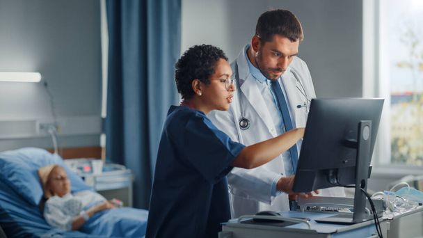 Hospital Ward: Caucasian Doctor Talks With Professional Black Head Nurse, They Use High-Tech Computer. In Background Patient in Bed Recovering after Successful Surgery. Health Care Specialists - Foto, Imagem
