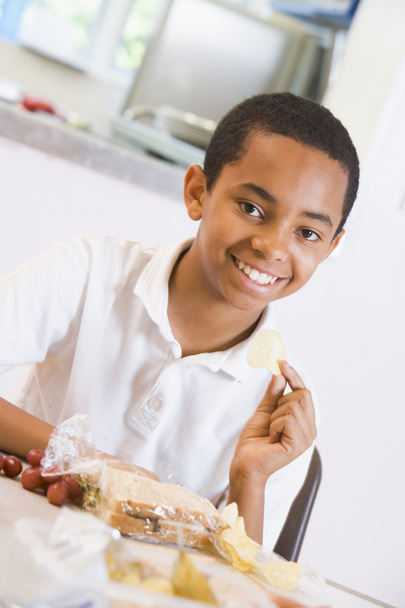 Schoolboy enjoying his lunch in a school cafeteria - Photo, Image