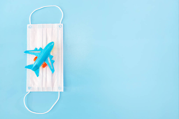 Medical mask and toy plane on a blue background. Copy space. - Фото, зображення