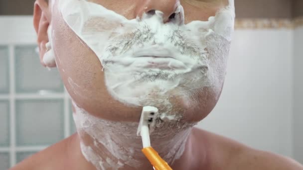 młody dorosły mężczyzna golenie przez brzytwa ostrze - Materiał filmowy, wideo