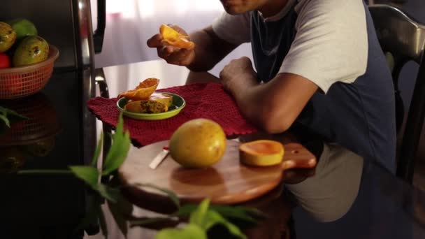 um homem indiano de meia idade comendo manga madura saborosa sentado ao lado de uma mesa - Filmagem, Vídeo