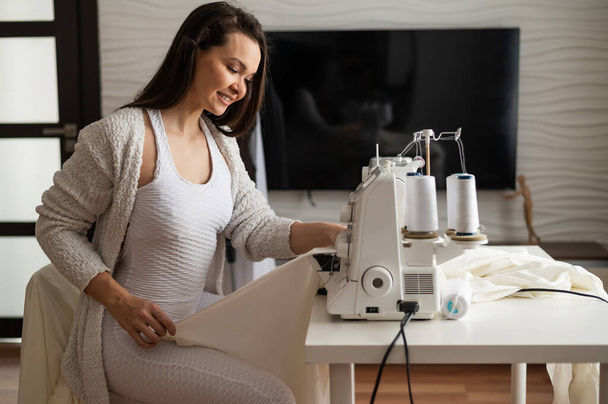 Caucasian woman sews to order at home. Work space of a seamstress in the living room - Photo, image