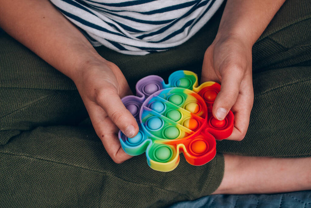 Крупним планом хлопчики рук використовують веселку поп-іграшку. Push Bubble Viget сенсорна іграшка миється і багаторазово використовується силіконова іграшка для полегшення стресу. Антистресова іграшка для дитини з особливими потребами
 - Фото, зображення
