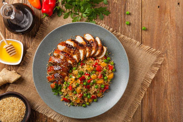 Grilled chicken breast in teriyaki sauce. Served with brown rice and vegetables. Top view. Flat lay. - Foto, immagini