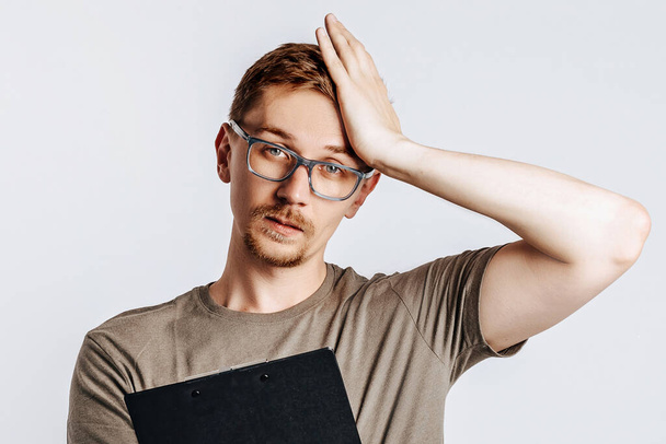 Young handsome man in glasses holding folder for papers with documents, student, worker looks data information, posing for photo isolated on gray background. - Φωτογραφία, εικόνα