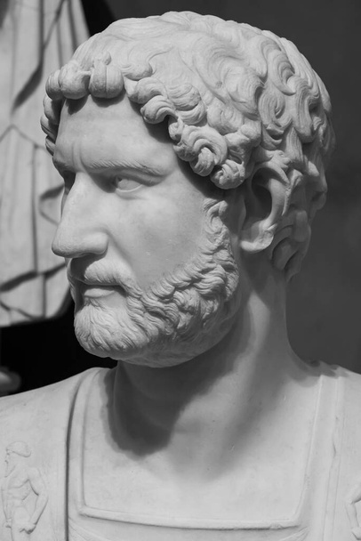 Close-up on profile of head of ancient roman marble statue representing a bearded mature man - black and white photo - Photo, Image
