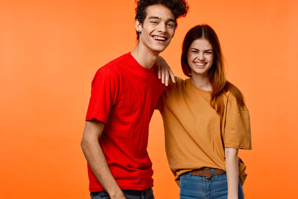young couple in multicolored t-shirts joy cropped view orange background - Photo, Image
