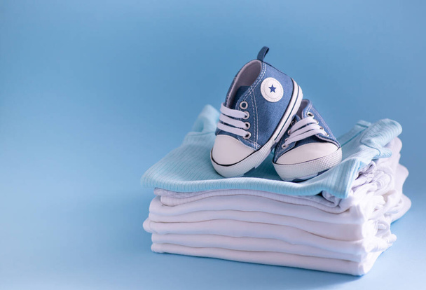 Nahaufnahme von Babybekleidung und Accessoires auf blauem Hintergrund - Foto, Bild