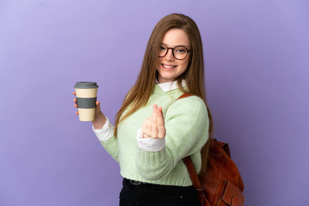 Adolescente étudiante fille sur fond violet isolé faisant geste d'argent - Photo, image