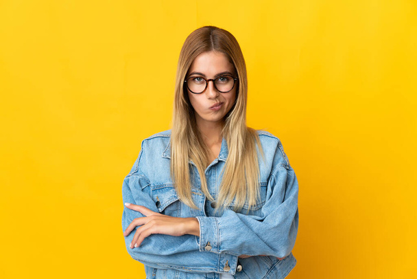 Young blonde woman isolated on yellow background with unhappy expression - Photo, Image