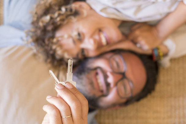 Glückliches junges Paar zeigt aufgeregt neue eigene Hausschlüssel, lächelnd liebevolles erwachsenes Ehepaar überglücklich Erstkäufer ziehen in Mietwohnung um - Foto, Bild