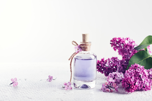 Flacone di profumo e fiori lilla viola. Concetto di profumeria e cosmetici. - Foto, immagini