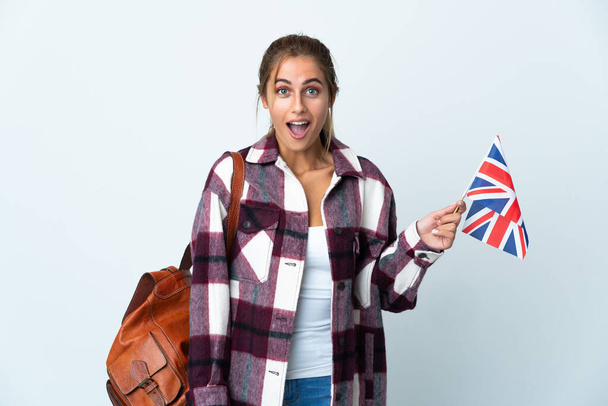 Jovem segurando uma bandeira do Reino Unido isolada em fundo branco com expressão facial surpresa - Foto, Imagem