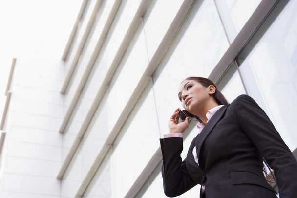 Businesswoman talking on cell phone outside modern office - Фото, изображение