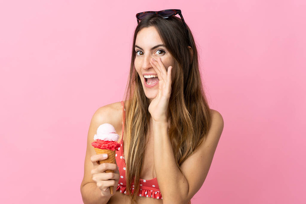 Jeune femme caucasienne tenant une crème glacée isolée sur fond rose criant avec la bouche grande ouverte - Photo, image
