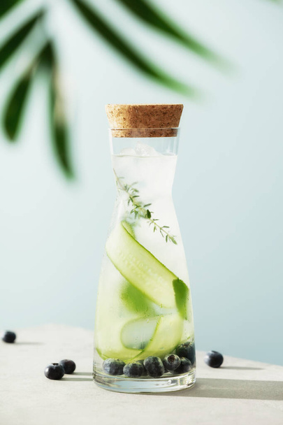 Summer infused water with cucumber, blackberry and rosemary on blue sky background, summer refreshment concept - Photo, image