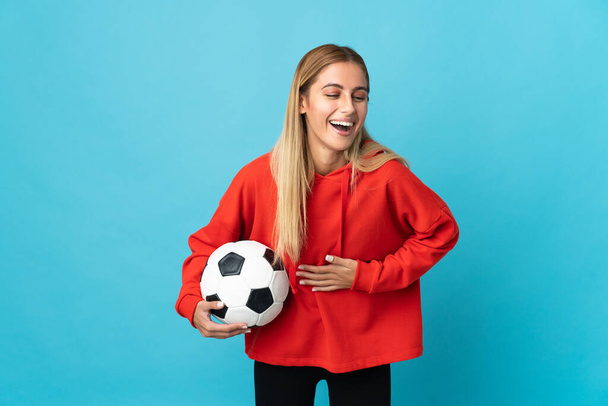 Junge Fußballerin auf blauem Hintergrund, die viel lächelt - Foto, Bild