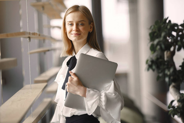Businesswoman standing in the office with a laptop - Photo, image