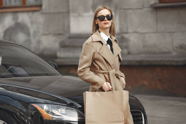 Woman standing by the car with shopping bags - Foto, Imagem