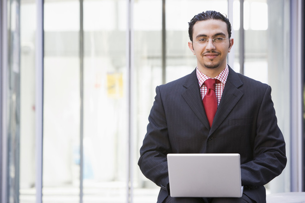 Businessman using laptop outside office - Фото, изображение