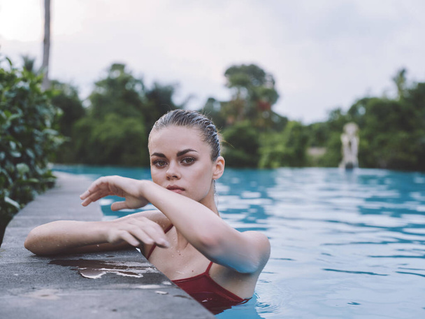 Frau im Urlaub auf der Insel schwimmt im Pool und hohe Bäume im Hintergrund - Foto, Bild