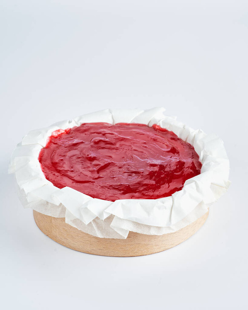 Mini cheesecake met rood fruit jam topping op recycle Mini Houten bakvorm, witte achtergrond, ruimte voor tekst, selectieve focus. - Foto, afbeelding