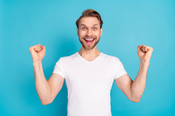 Portrait of astonished positive man fists up open mouth shout yes isolated on blue color background - Foto, Bild