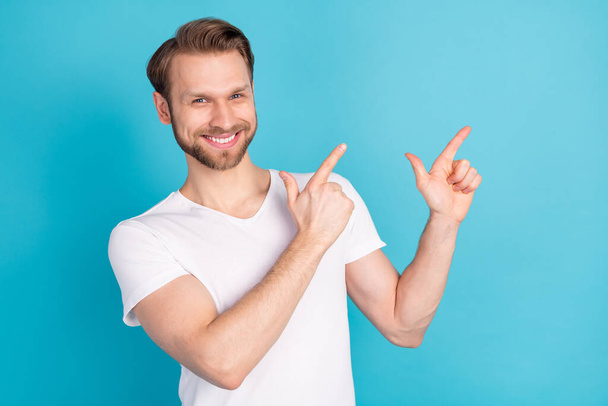 Photo of positive person toothy smile direct two fingers empty space offer isolated on blue color background - Foto, Imagen