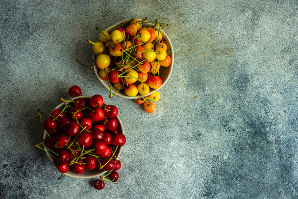 Fondo de verano con cerezas dulces maduras en tazones de piedra - Foto, Imagen