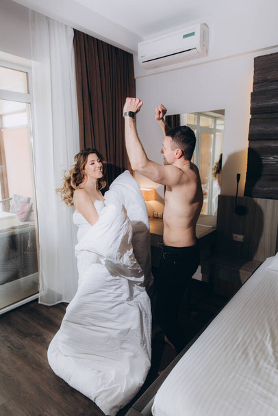 Beautiful joint emotional and cheerful gatherings of the bride and groom in white clothes in the room - Fotografie, Obrázek