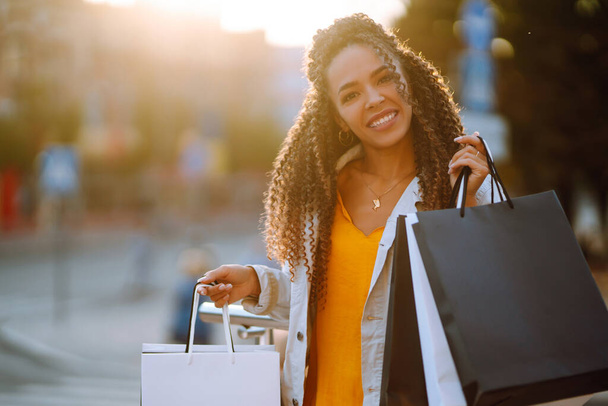 Młoda kobieta z torbami na zakupy chodząca ulicą. Koncepcja sprzedaży, zakupów, turystyki i szczęśliwych ludzi.  - Zdjęcie, obraz