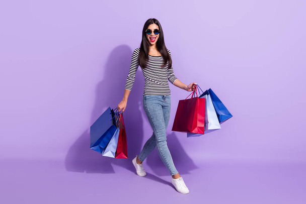 Full size photo of happy excited beautiful woman shopaholic go walk enjoy weekend isolated on violet color background - Fotoğraf, Görsel