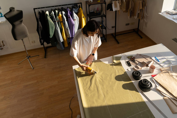 Процесс шитья и резки: работа портнихи с узорами на ткани для коллекции в мастерской - Фото, изображение