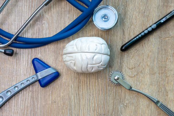 Zdjęcie figurki mózgu w środku i stetoskop, młotek, aby sprawdzić odruchy. Zdjęcie może być wykorzystane do zilustrowania dowolnego artykułu lub strony internetowej o medycynie.  - Zdjęcie, obraz