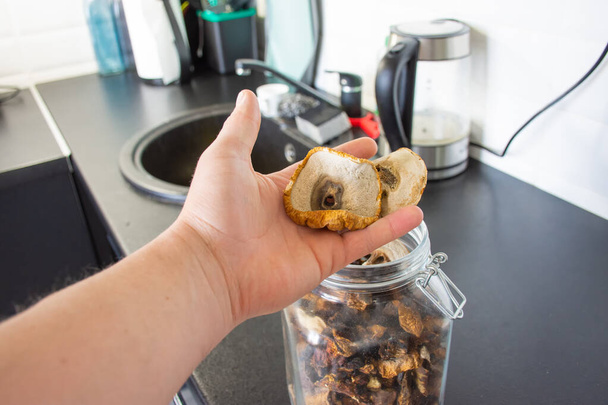 Фото сушених грибів, які демонструє чоловік, тримаючи його в руці зі скляною банкою, наповненою грибами на фоні. Фото можна прикріпити до статті про гриби про альтернативну медицину
 - Фото, зображення