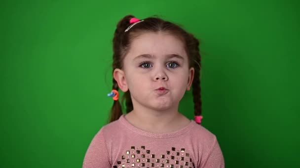 Wütendes kleines Mädchen, grüner Hintergrund, kleines Mädchen mit Zöpfen. - Filmmaterial, Video