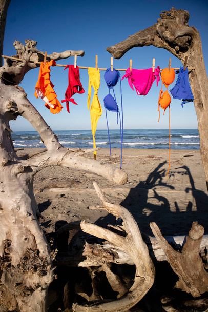 Fotoshooting von Bademode für Frauen, die im Sommerwind eines freien Strandes zum Trocknen herumhängt.  - Foto, Bild