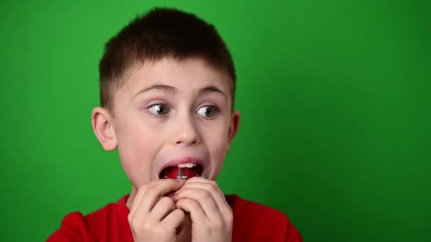 a gyermek a lemezt a felső ívelt fogakra helyezi, összehangolva a felső fogak görbületeit. - Felvétel, videó