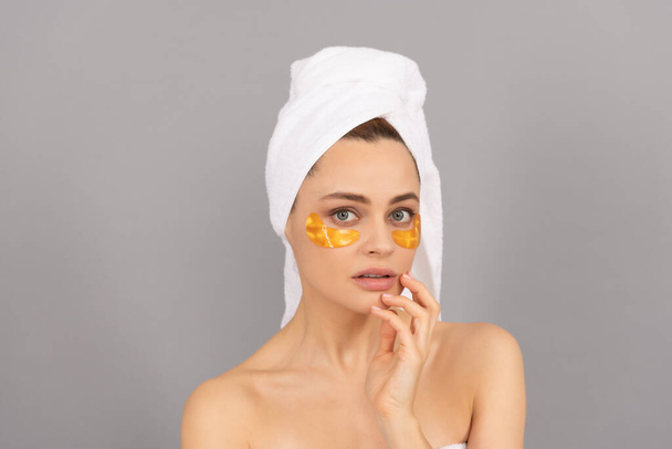 sensuele dame met badstof handdoek gebruik gezicht gouden ooglapje voor de huid, hydrogel - Foto, afbeelding