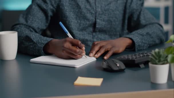 Κοντινό πλάνο αφροαμερικάνος μαύρος άνδρας χέρια κρατώντας σημειώσεις στο σημειωματάριο χρησιμοποιώντας ένα στυλό - Πλάνα, βίντεο