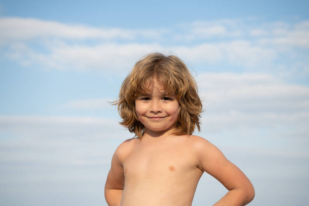 Портрет щасливого безсорочного хлопчика, який посміхається влітку на фоні неба, хлопчик
 - Фото, зображення