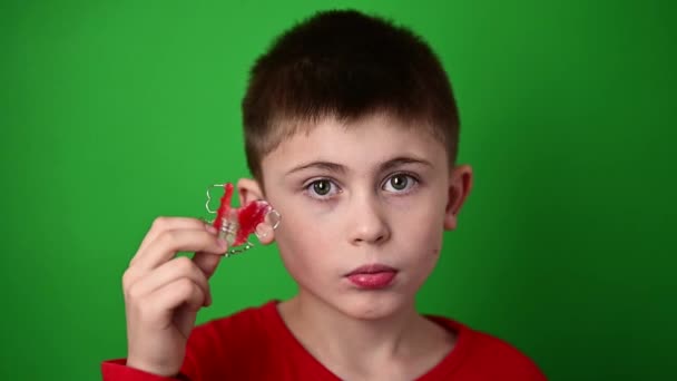 Ένα εννιάχρονο αγόρι κρατάει μια οδοντιατρική πλάκα ευθυγράμμισης, ένα βδέλυγμα και μια επίδειξη μιας οδοντικής πλάκας ευθυγράμμισης.. - Πλάνα, βίντεο