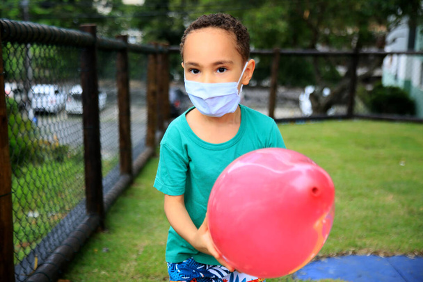 salvador, bahia, brasil - 15 de maio de 2021: criança usando máscara de proteção contra coronavírus brinca em um playground na cidade de Salvador - Foto, Imagem