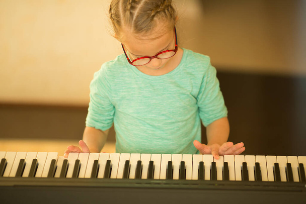 Egy Down-szindrómás lány zongorázni tanul. - Fotó, kép