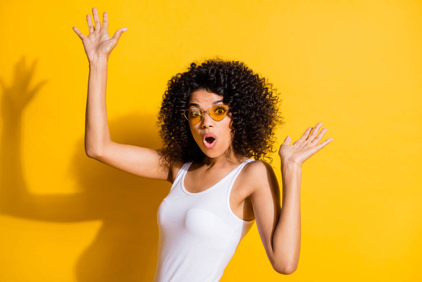 Portrait of impressed dark skin lady open mouth raise hands palms clubbing isolated on yellow color background - Photo, image